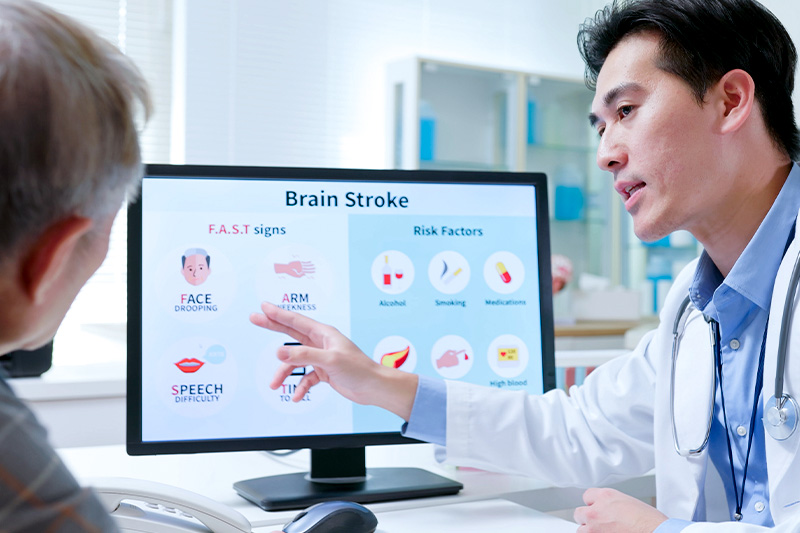 Interventional cardiologist showing a patient a picture on a computer of stroke risks.