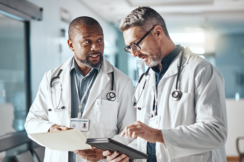 Two doctors speaking to one another in a hallway about cardiac and vascular services.