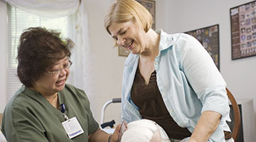 A nurse assisting a patient in her own home as she tries to stand up